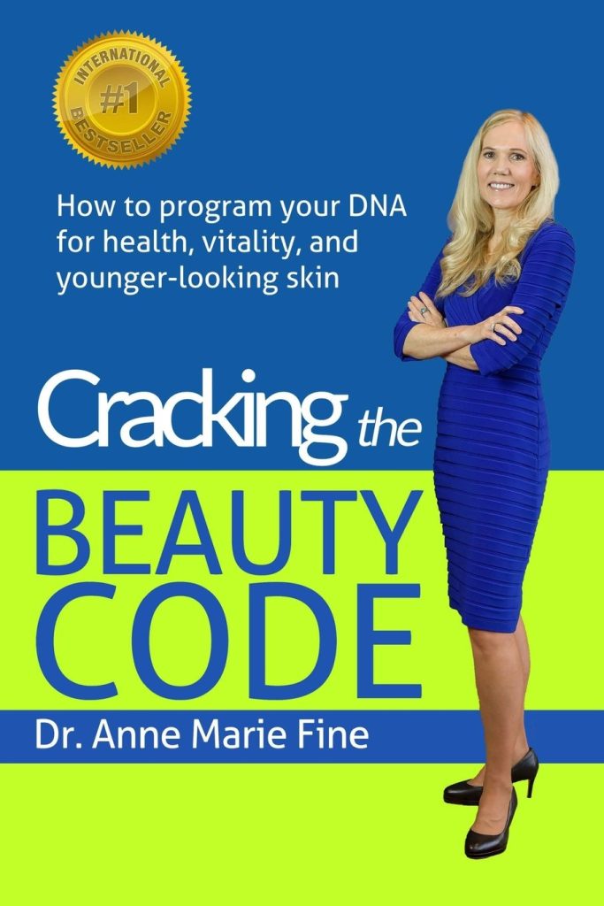 The cover for the book: "Cracking The Beauty Code" by Dr. Anne Marie Fine. It is blue and green with a photo of a blonde woman on the cover in a blue dress. (Dr. Fine)