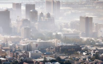 A photo of a cityscape in the daytime in the sunshine but the sky is thick with smog.