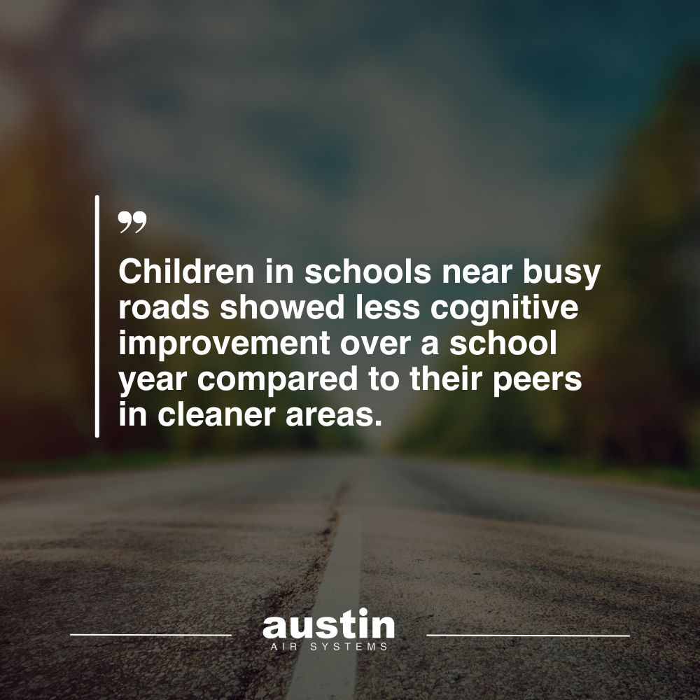 In-blog graphic to highlight the fact: “Children in schools near busy roads showed less cognitive improvement over a school year compared to their peers in cleaner areas,” written in white writing over a stock image of a close up of a road that is blurred in the background. The words: “Austin Air Systems” are located in the bottom center of the image, in white text.