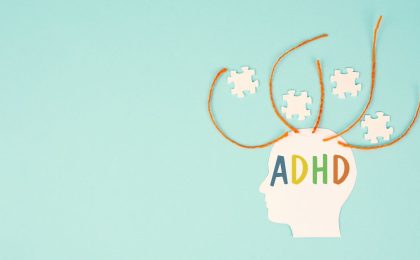 A baby blue background with a side view of a human head in white with ADHD in colorful text over the top portion. There are four orange threads coming out of the scalp with four white puzzle pieces arranged between the threads.