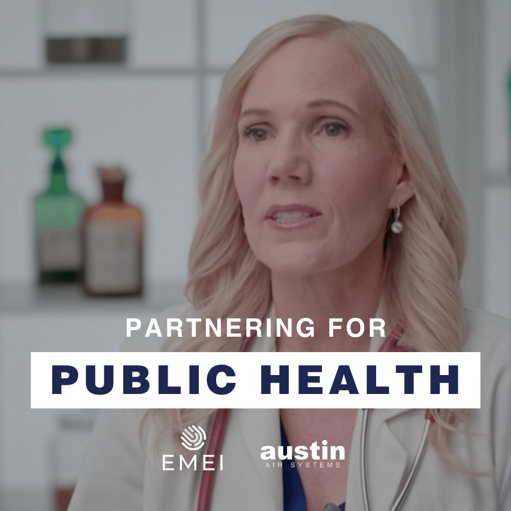 A photo of Dr. Anne Marie Fine in a lab setting. She is a good looking blonde woman, wearing a white lab coat and a red stethoscope. The text: “Partnering for Public Health” are at the bottom with the logos for EMEI Global and Austin Air Systems in white.