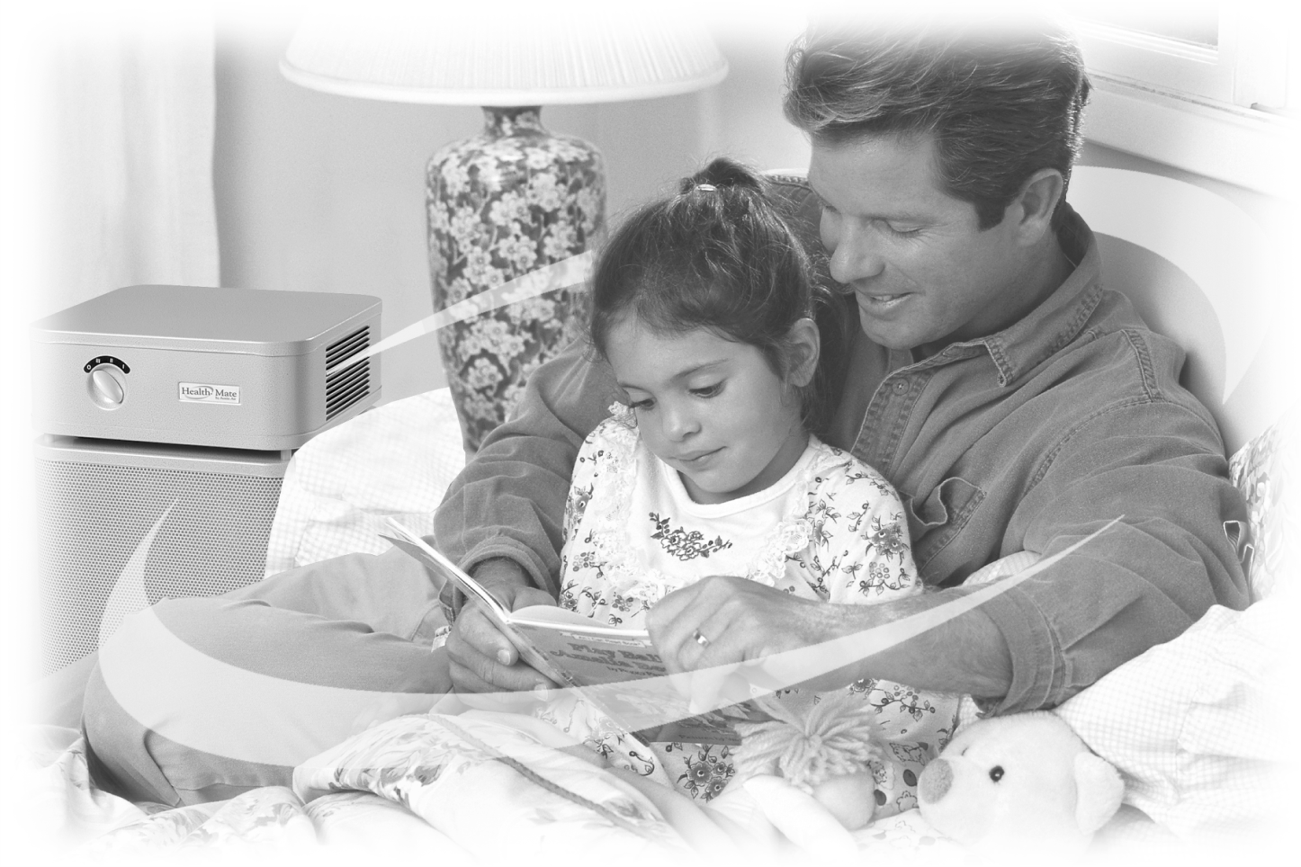 A black and white photo of a father reading to his daughter on an overstuffed chair. In the left corner, you can see an Austin Air unit. This is an old ad from the 1990s and it shows that the design of Austin Air purifiers hasn’t changed in the company’s history.